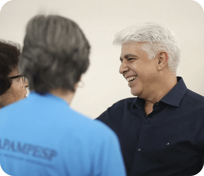 Walter Coelho, palestrante de vendas conversando e sorrindo com participantes de evento corporativo.